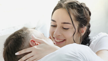 cheerful brunette woman touching face of boyfriend at home.