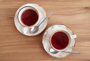 Red fruit tea in trendy ceramic white cups with brown decor on wooden table. Food background in rustic style. Copy space. Flat lay.