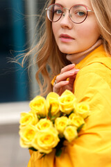 Naklejka premium woman in yellow raincoat with yellow flowers close up in autumn