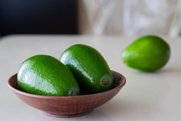 Ripe avocado in a brown plate on a light background.