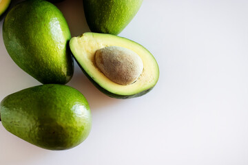 Several ripe avocados on a light background.
