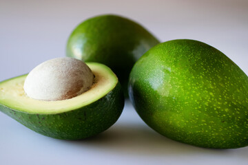 Several ripe avocados on a light background.