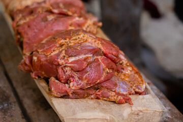 Freshly juicy marinated meat with spices and onion on wooden board at summer local food market - close up view. Outdoor cooking, gastronomy, cookery, street food concept