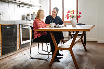 A side view of the concentrated doctor writing a prescription and looking at her elderly patient