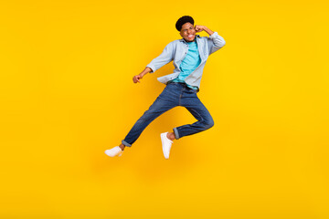 Naklejka na ściany i meble Photo of charming funky dark skin man wear jeans shirt jumping high practicing karate isolated yellow color background