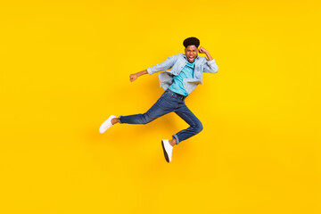 Fototapeta na wymiar Photo of strong cool dark skin guy dressed denim shirt practicing karate jumping high isolated yellow color background