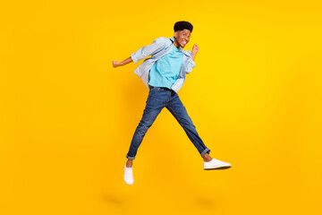 Fototapeta na wymiar Photo of lucky funky dark skin man wear jeans shirt jumping high rising fists smiling isolated yellow color background