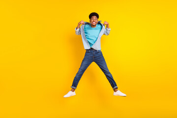 Fototapeta na wymiar Photo of strong attractive dark skin guy dressed denim shirt showing muscles jumping high isolated yellow color background