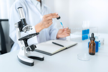 Scientist woman holding dropper to dropping solution sample on the glass plate for microscope