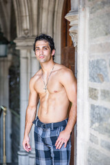 Wearing a cross necklace and half naked, a handsome, muscular guy is standing at a old fashion doorway and waiting for you.