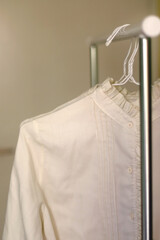 White and beige blouses on a clothing rack. Selective focus.