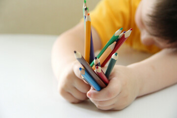 hands with pencils. The child is holding a lot of colorful pencils for drawing.