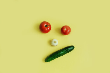 Emotions depicted by vegetables, tomatoes, garlic, cucumber on a yellow background, top view, copy space.