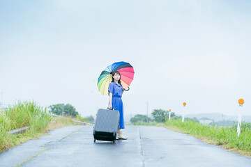 スーツケースとカラフルな傘を持つ女性