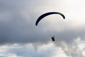 Naklejka na ściany i meble Adventurous People Flying on a Paraglider around the mountains. Savona, British Columbia, Canada.
