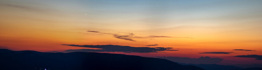 Panorama of the Carpathian mountains at sunset and the lights of the village in the haze
