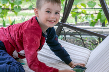 Boy with smartphone on garden sofa in spring in the garden.