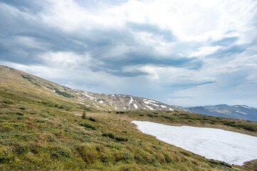 Spring mountains in the snow on the background of a green forest