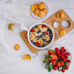 Breakfast, Mini pancakes with strawberries, croissants and avocado, Delicious summer food, Top view on a light marble background