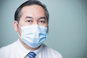 Close up Asian businessman wearing a white shirt with a blue tie and wear a medical mask to prevent the coronavirus. Looking at the camera. Protect COVID-19, Social distancing, new normal concept.