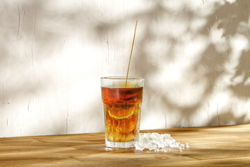 Cold ice tea on wooden desk and wall background of free space 