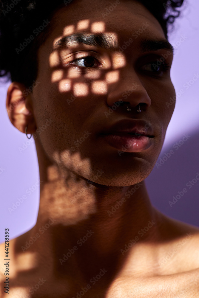 Wall mural close-up verticale portrait of latino young man face in texture shadows, lights on eye. trans gender