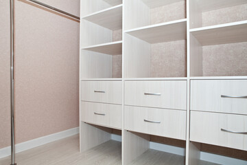 A fragment of the interior of the dressing room with drawers, shelves and rods for hangers