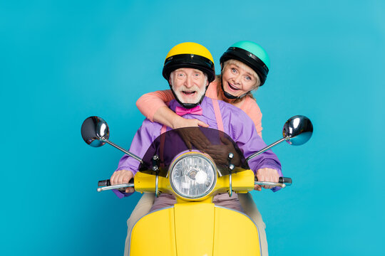 Photo of positive grey haired couple wear helmet ride motorbike hug isolated on pastel blue color background