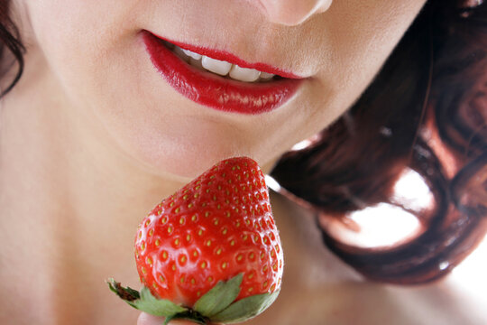 Roter Mund einer Frau an roter Erdbeere