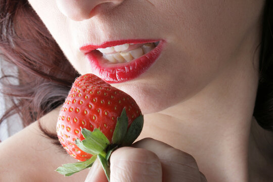 Sinnlich roter Mund einer Frau und eine rote Erdbeere