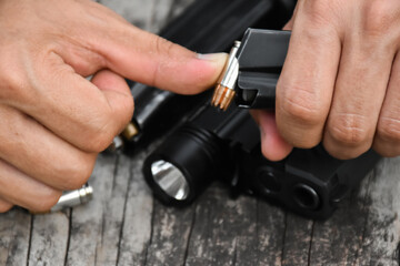 Close-up of a man hands holding and loading gun magazine in the pistol at the shooting range.