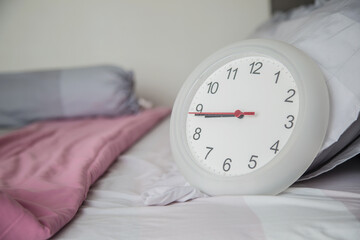 White clock on the bed as wake up at morning concept.