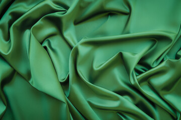 Elegant soft abstract green background. Delicate silk waved fabric with copy space for design projects