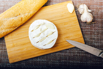 DIY baked cheese camembert instruction step by step. step 2 make cuts on the camembert and insert the garlic into the cuts.cheese with white mold.moldy cheese