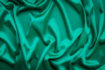 Elegant soft abstract green background. Delicate silk waved fabric with copy space for design projects