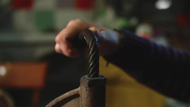 Leather craftsman at work. Close up tilt of his hands using a hand rivet press in order to puncture leather