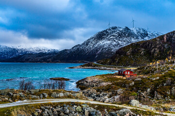 Rote Hütte am Ufer des Fjord an einem stürmischen Tag in Troms, in der Nähe von Tromsö, Norwegen. interessante Lichtstimmung mit dem dunklen, aufgewühlten Meer und Wolken und Holzhaus. 