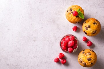 Freshly baked stracciatella cupcakes garnished with mint leaves beside raspberries on grey countertop