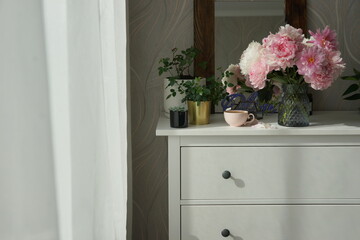 Fototapeta na wymiar Bouquet of pink peonies on the dresser in the bedroom