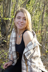 Smiling girl with light brown hair and a checkered shirt, sunny warm day.