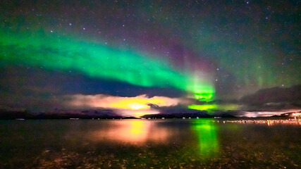 Nordlichter über dem Fjord in Troms bei Tromsö. Aurora Borealis in the sky, heavenly light in the dark night. the lady dance in the sky. Polarlicht, Nordlicht in Norwegen