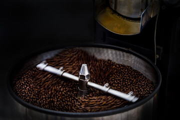 fresh coffee beans and roasted spinning cover professional machine close up and selective focus on dark