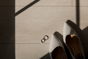 Wedding rings of the newlyweds lying on the floor with a beautiful shadow