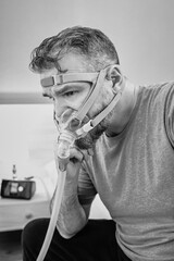 Unhappy shocked man with chronic breathing issues surprised by using  CPAP machine sitting on the...
