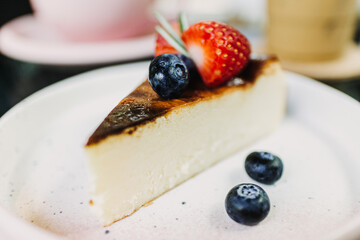 Burnt Strawberry Cheesecake served on white plate with some berries.