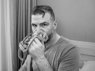 Unhappy shocked man with chronic breathing issues surprised by using  CPAP machine sitting on the...