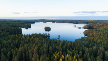 Obraz premium Aerial view of lake and colorful autumn forests in Finland. Sunset sky. Drone photography.