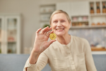 An elderly woman holds a bitcoin coin in her hand. Happy retirement life concept