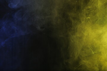 Artificial magic smoke in blue yellow light on black background