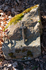 Fototapeta na wymiar Small simple cross on stone with moss in old churchyard. Winniki (village in Lobez County, West Pomeranian Voivodeship), Poland.